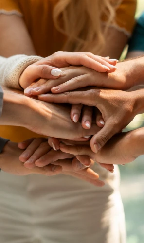 Manos de varias personas apiladas como gesto de colaboración